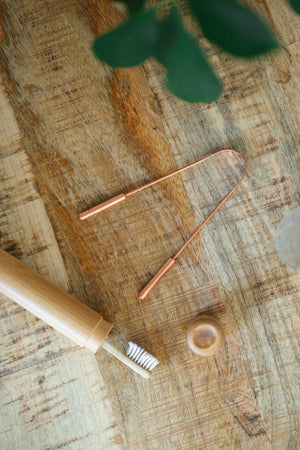 Kopero Kobbertungeskraber, på et træbræt ved siden af en tandbørste af bambus